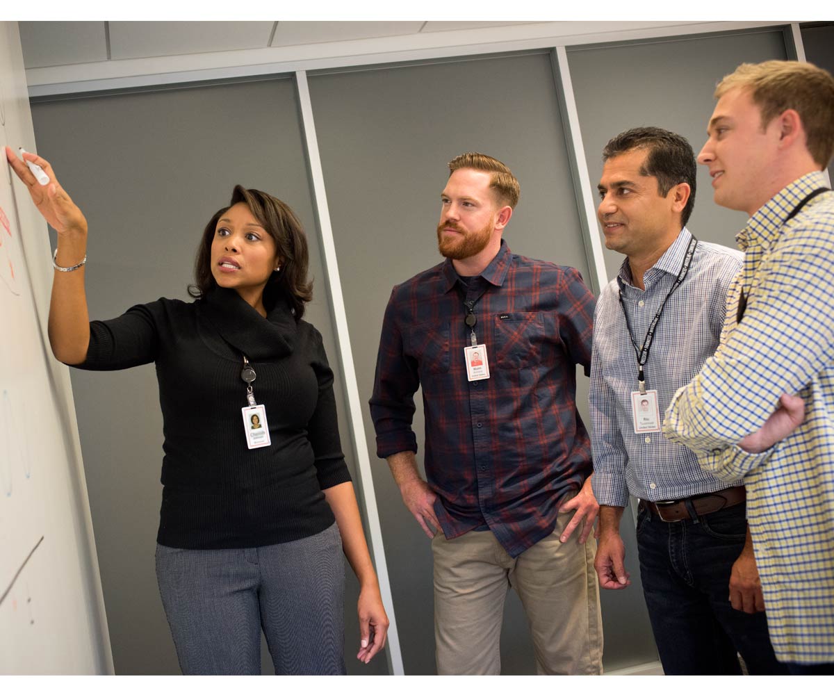 Associates talking with one another at a whiteboard