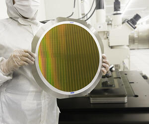 Image of a technician holding a silicon wafer disc in a cleanroom